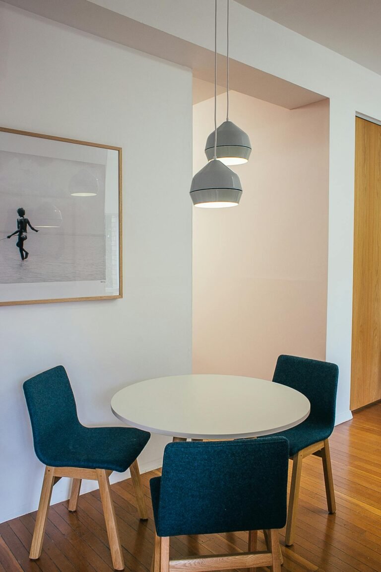 From above of comfortable soft chairs placed near round table in modern apartment decorated with framed photo and creative lamps